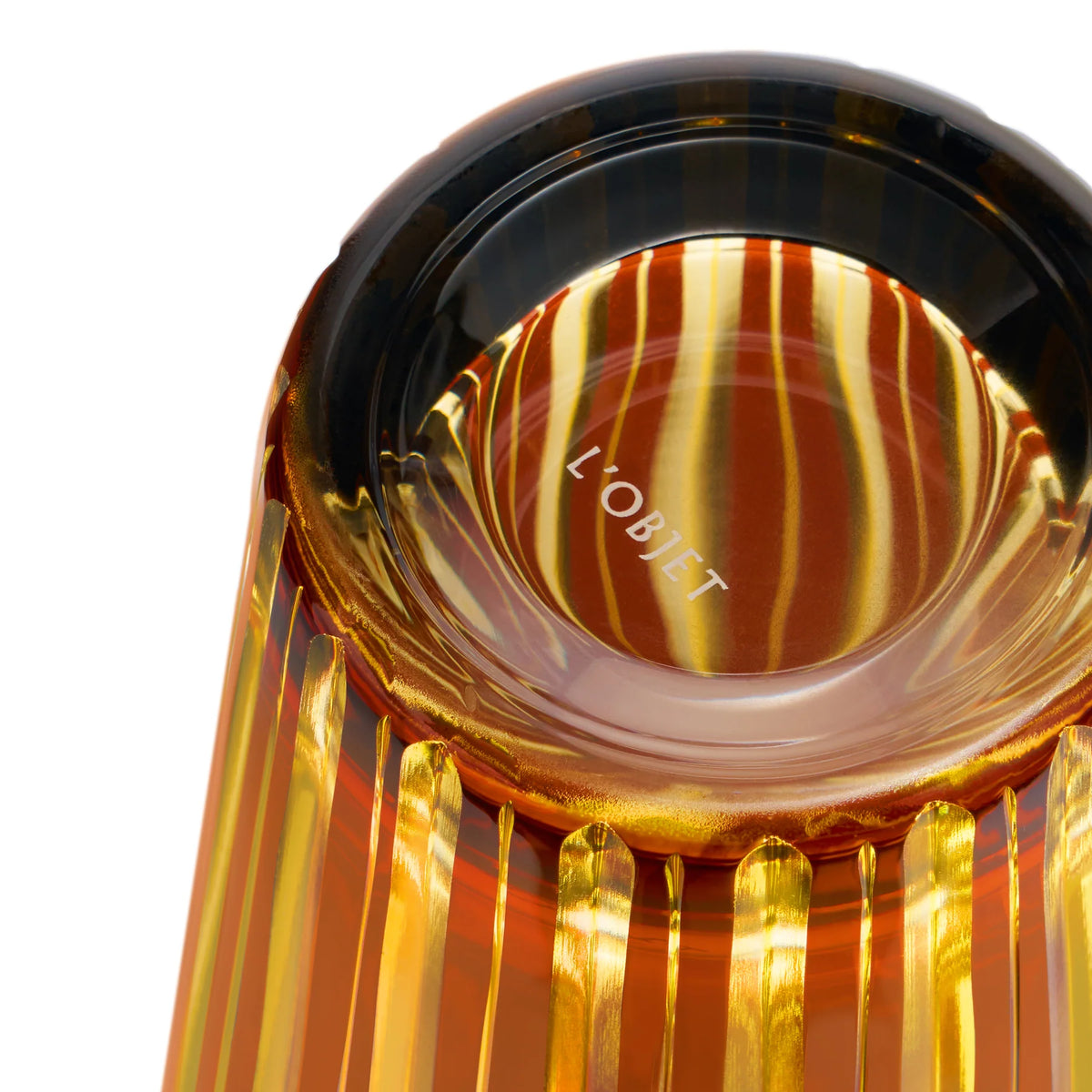 Close-up of the base of an amber Prism Cocktail Shaker with vertical ridges and striped reflections. The bottom features the L’Objet logo in white, showcasing the elegance of this hand-crafted glassware.