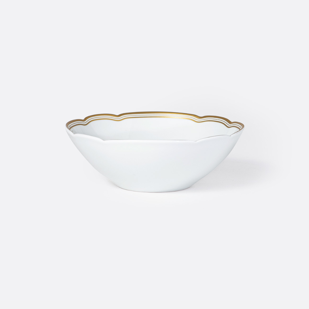 The Pompadour bowl by Bernardaud features white porcelain with gently scalloped edges and a delicate gold rim, reminiscent of classic Limoges dinnerware, shown against a plain light gray background.