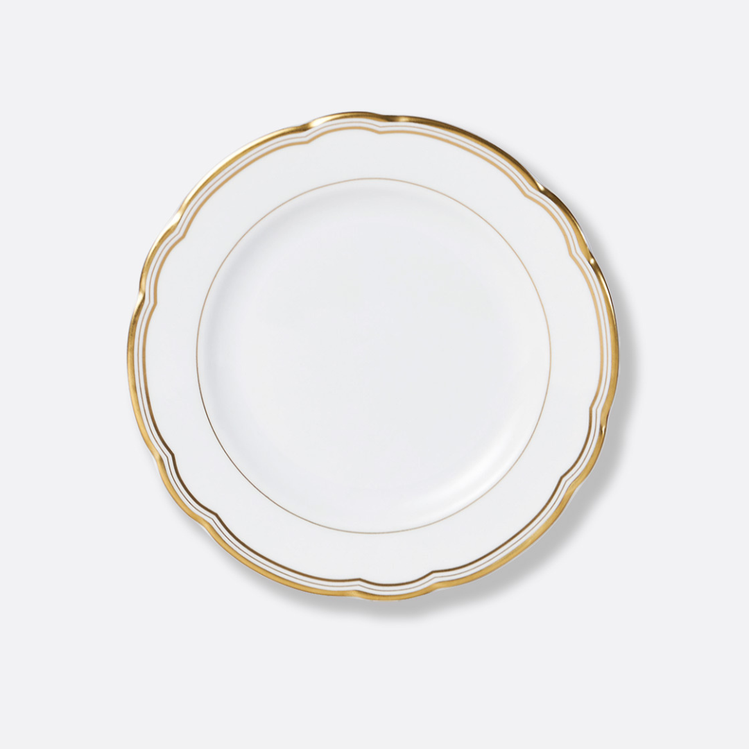 The Pompadour plate by Bernardaud features white porcelain, a scalloped edge, and gold trim, shown from above against a light gray background—an elegant piece from the renowned French brand’s fine dinnerware collections.