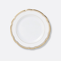 The Pompadour plate by Bernardaud features white porcelain, a scalloped edge, and gold trim, shown from above against a light gray background—an elegant piece from the renowned French brand’s fine dinnerware collections.