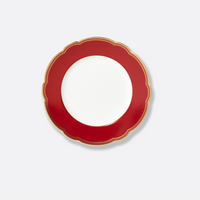 The Bernardaud Pompadour plate, a round white dish with a wide red scalloped and gold-trimmed border, is showcased against a plain light gray background.