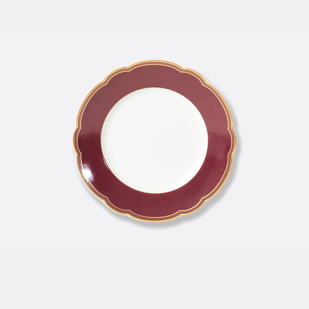 The Pompadour plate by Bernardaud features a round porcelain design with a white center, wide dark red scalloped border, and thin gold trim, showcasing classic elegance from Limoges, France. Displayed on a plain light gray background.