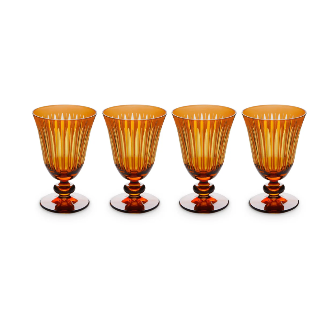 The Prism Wine Glass Set of 4 by L'Objet features amber hand-cut glass goblets with vertical ridges and rounded stems, arranged in a straight line against a white background, adding elegance to any collection.