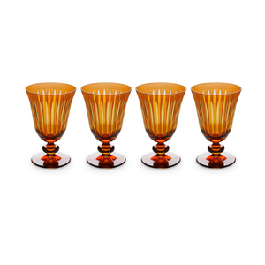 The Prism Wine Glass Set of 4 by L'Objet features amber hand-cut glass goblets with vertical ridges and rounded stems, arranged in a straight line against a white background, adding elegance to any collection.