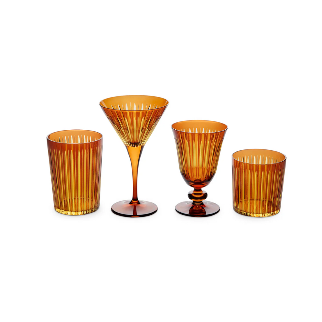 The Prism Martini Set of 4 by L'Objet features four amber-hued hand-cut glassware pieces—tumbler, martini glass, goblet, and short glass—with vertical ridges, displayed side by side on a white background.