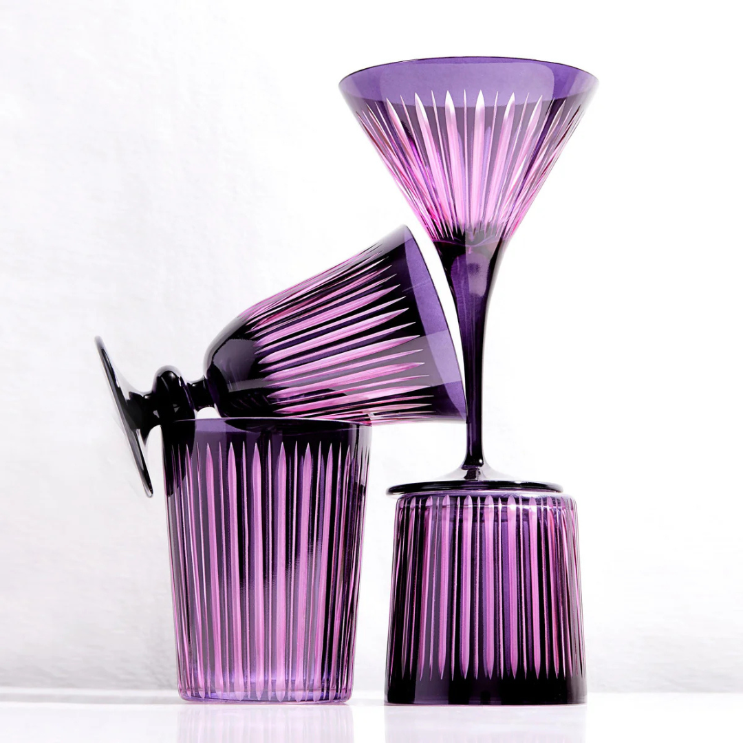 The L'Objet Prism Martini Set of 4 features elegant martini glasses in bold purple hues with vertical etched lines, stacked artistically to create a striking accent for any glassware collection against a white background.