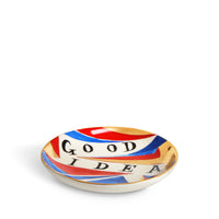The Good/ - Bad Idea Plate by Ruan Hoffmann for L'Objet features bold “GOOD IDEA” text, vibrant red, blue, white, and gold swirls, and is part of the Vide Poche Plates collection.