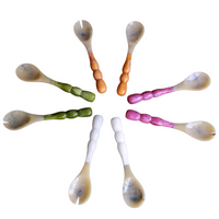 Eight Beatriz Ball Resin Rio Bubble Salad Servers with vibrant orange, green, white, and pink handles are arranged in a circle on a white background, their bubble handles radiating outward like spokes on a wheel.