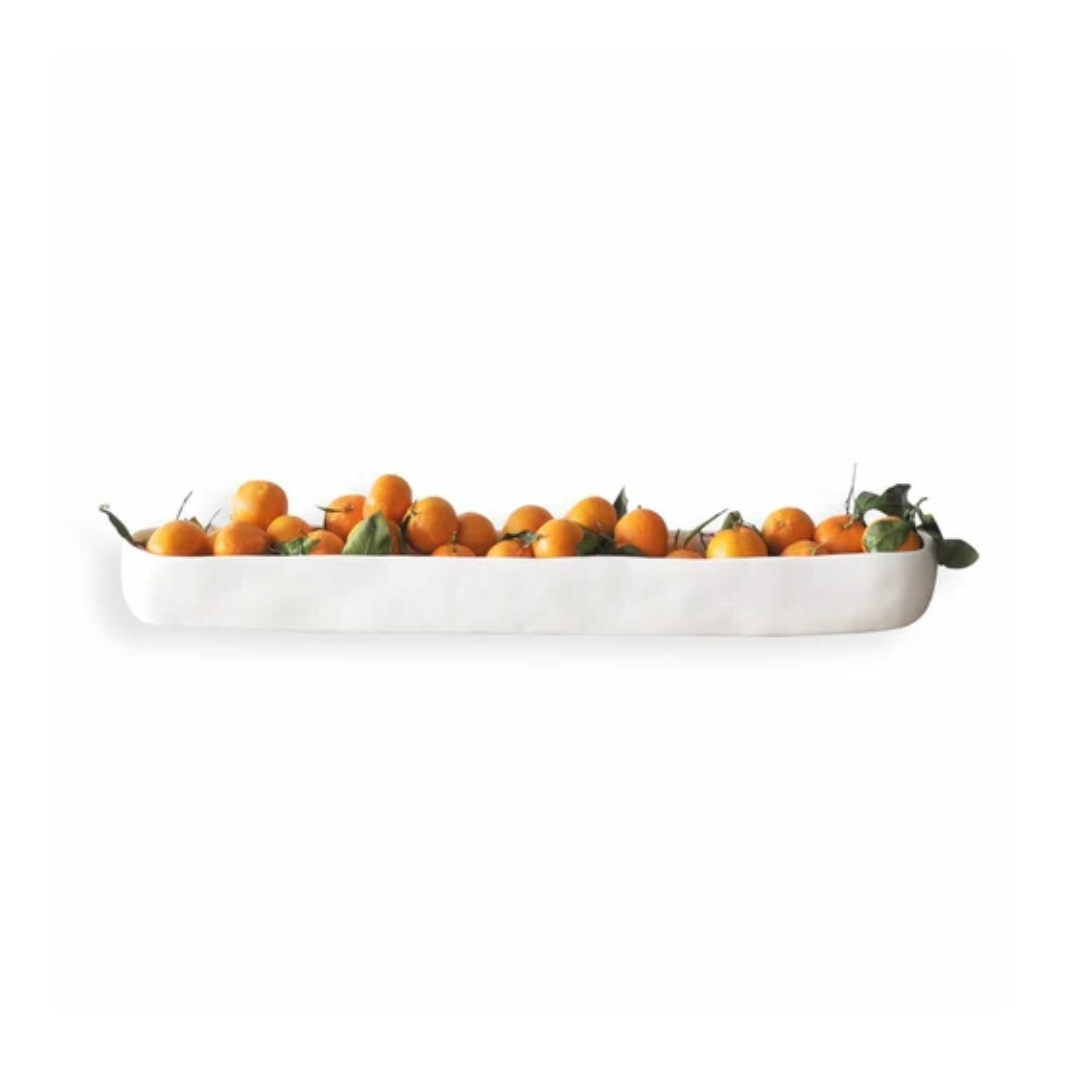 The Tina Frey Resin Trough White Long, filled with oranges and green leaves, makes elegant table decor against a plain white background.