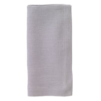 The Bodrum Riviera Napkin Set of 4 features neatly folded, light gray stone-washed linen napkins with a simple stitched border, displayed on a white background.