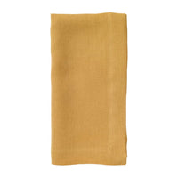 The Bodrum Riviera Napkin Set of 4 features mustard yellow stone-washed linen napkins with stitched edges, neatly folded and displayed on a white background.