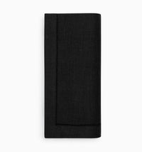 A neatly folded black Festival Napkin from Sferra, made of European linen and featuring a stitched border, rests on a white background.