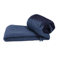 Two Stitching Throw blankets by Mantas Ezcaray, handmade in blue wool: one folded flat, the other rolled with visible stitched edging, set against a white background.