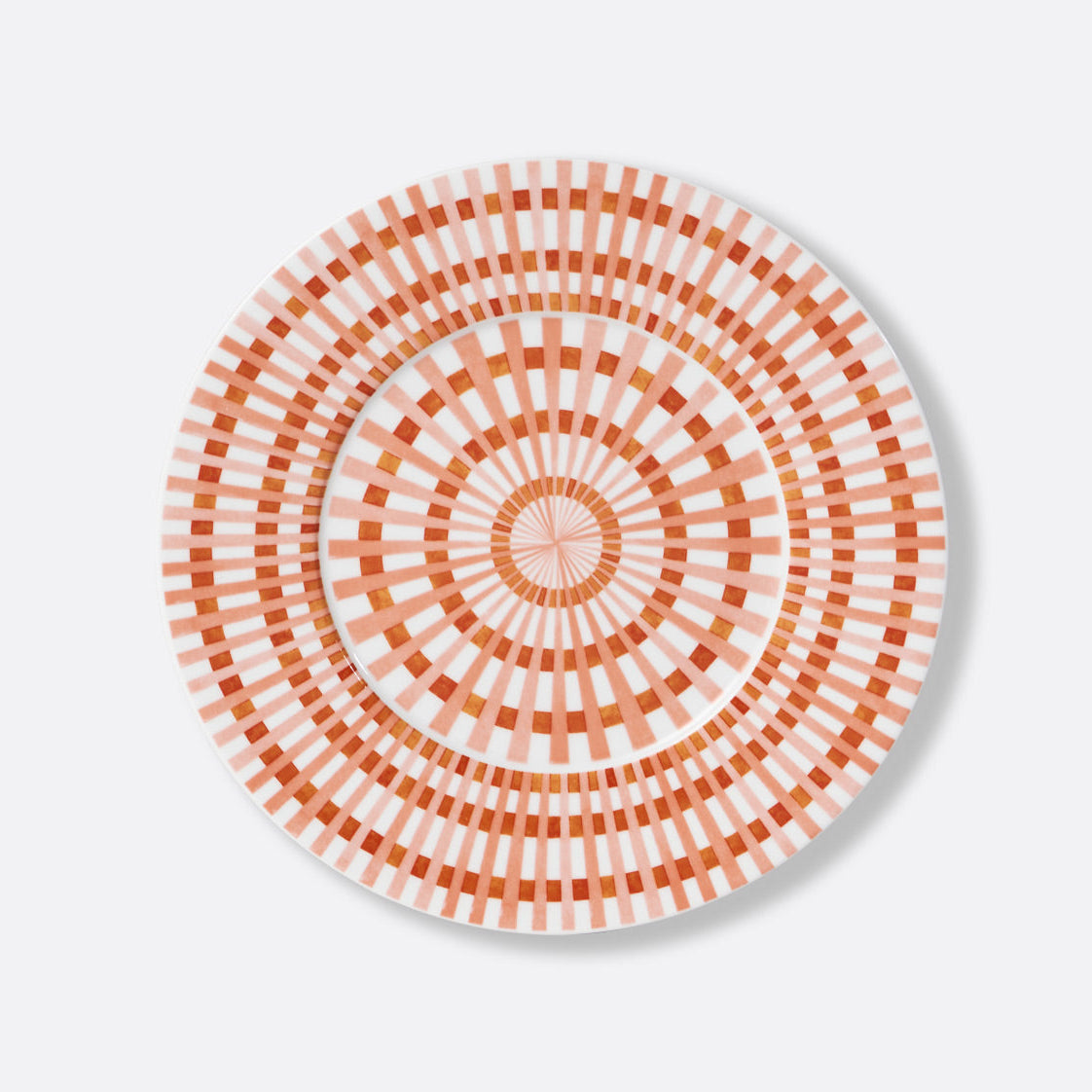 The Terra Rosa Dinnerware by Bernardaud features a round plate with orange and white geometric concentric circles and radiating lines for a striking sunburst effect. Made in Limoges, France.