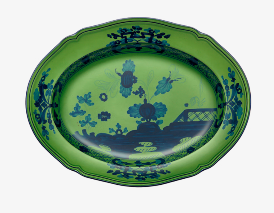 The Oriente Italiano Dinnerware Malachite by Ginori 1735 is an oval green ceramic platter featuring dark blue floral and landscape motifs around the scalloped rim and center, elegantly set against a white background.