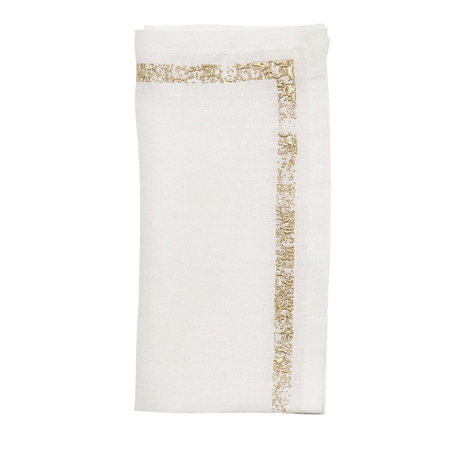 The Kim Seybert Impression White & Gold Napkin Set of 4 features neatly folded white linen napkins accented with decorative gold metallic stitching along two edges, displayed against a plain white background.