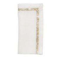 The Kim Seybert Impression White & Gold Napkin Set of 4 features neatly folded white linen napkins accented with decorative gold metallic stitching along two edges, displayed against a plain white background.