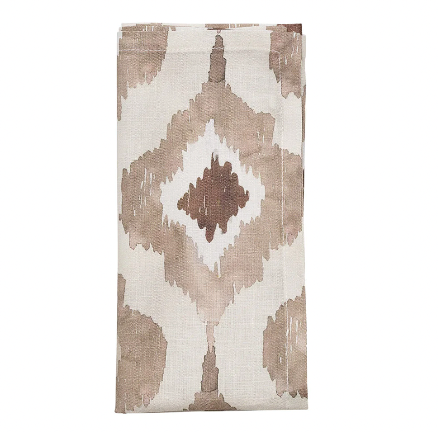 The Kim Seybert Watercolor Ikat Napkin Taupe Set of 4 features a folded beige linen napkin with a geometric diamond pattern in brown and taupe accents, displayed on a white background.