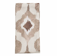 The Kim Seybert Watercolor Ikat Napkin Taupe Set of 4 features a folded beige linen napkin with a geometric diamond pattern in brown and taupe accents, displayed on a white background.