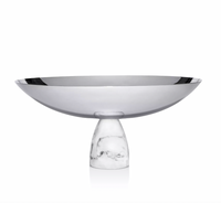 The Coluna Carrara Marble Fruit Bowl by Anna New York features a shiny silver metallic dish and a smooth Italian Carrara marble pedestal base, shown against a plain white background.