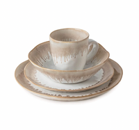 The Simon Pearce Burlington Dinnerware Bluff set includes a plate, salad plate, bowl, and mug, each crafted from ceramic with beige and white glaze and a rustic drip edge for an organic look.