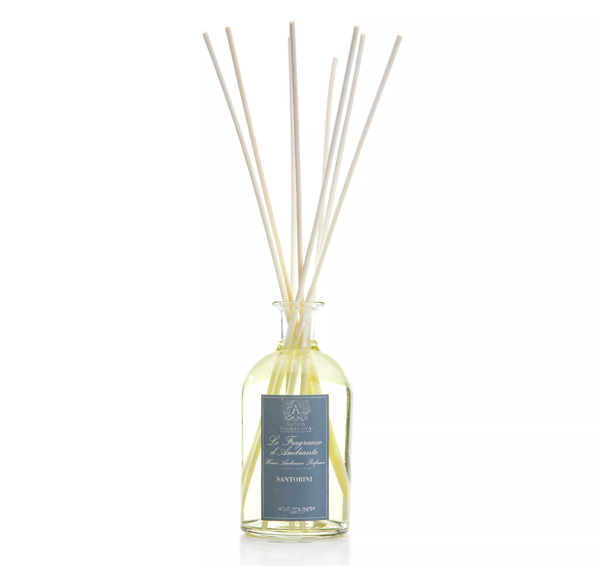 The Antica Farmacista/Harper Santorini Diffuser features a glass bottle labeled "Santorini" with long reeds, set against a white background, infusing your space with an elegant Mediterranean-inspired fragrance.