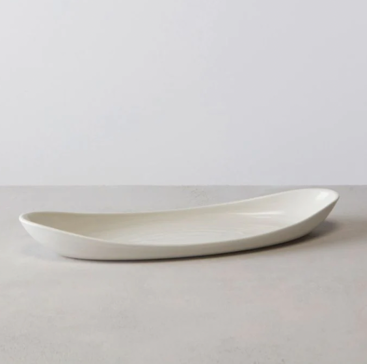 The Barre Serving Platter - Alabaster by Simon Pearce is a sleek, elongated white ceramic piece with gently curved edges, shown on a light gray surface against a minimalist background.