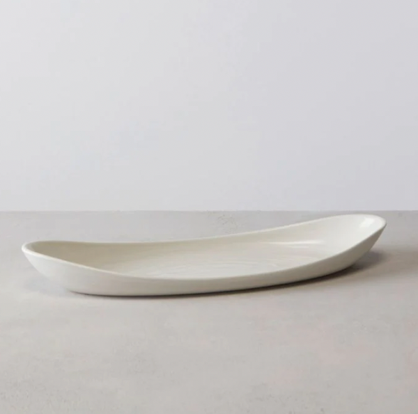 The Barre Serving Platter - Alabaster by Simon Pearce is a sleek, elongated white ceramic piece with gently curved edges, shown on a light gray surface against a minimalist background.