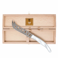 The Claude Dozorme Berlingot Fromage Cheese Knife features “FROMAGE” cut out on its stainless steel blade and comes displayed on a wooden box with a hinged lid and gold clasp.