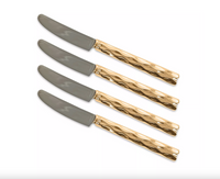 The Michael Wainwright Truro Gold Spreaders Set of 4 features silver blades and 24k gold-toned, textured handles—a stunning serveware set arranged diagonally on a white background, perfect as a unique hostess gift.
