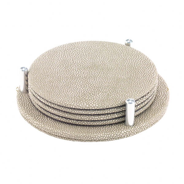 The Bodrum Stingray Coaster Set of 4 features textured, round beige coasters with a subtle metallic finish, stacked neatly in a matching holder with three vertical pegs for secure, stylish storage.