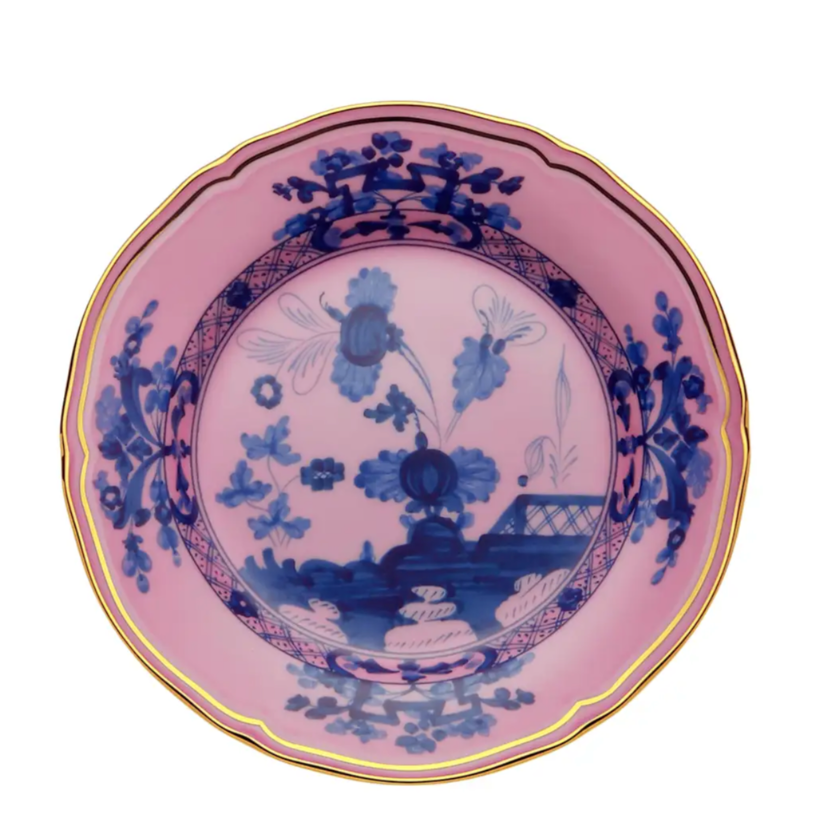 The Ginori 1735 Oriente Italiano Dinnerware Azalea is a round Italian porcelain plate with a pink background, detailed blue chinoiserie floral motif, and gold rim in a timeless traditional style.