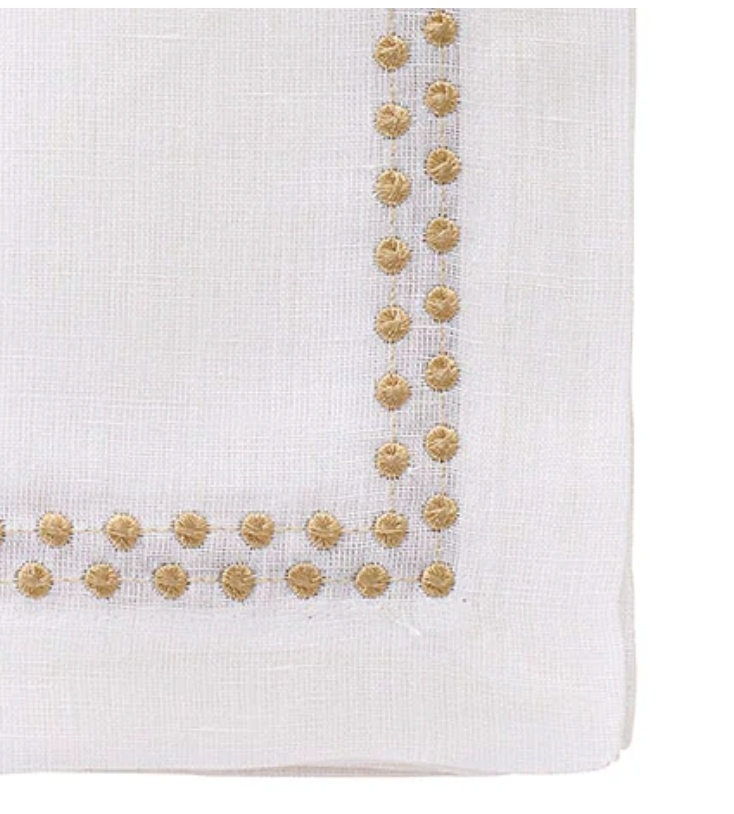 The Bodrum Pearls Napkin Gold Set of 4 features white linen napkins with decorative gold embroidered dots forming a square border, adding elegant style to any dinner setting.
