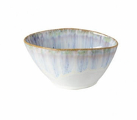 The Costa Nova Brisa Blue Dinnerware bowl features a rounded square shape, white base with blue vertical streaks, and a thin brown rim. This ceramic piece is empty and displayed against a plain white background.