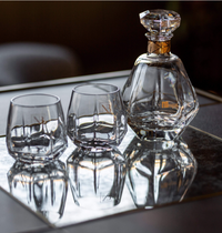 The Vista Alegre Gemstone Crystal DOF Set of 2 features exquisite tumblers, which shine elegantly on a mirrored tray and create stunning reflections beneath them.
