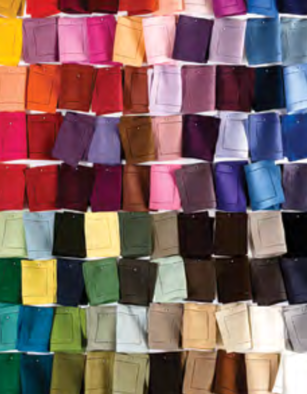 Rows of Sferra Festival Napkin Set of 4 fabric swatches in vibrant reds, pinks, purples, blues, greens, browns, and neutrals are pinned to a white background in a colorful and organized display.