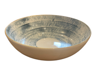 The Marie Daage Agate Dinnerware by Marie Daâge features a shallow ceramic bowl with a white exterior and a blue-and-white speckled interior, evoking luxury tableware, displayed on a white background.