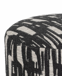A close-up of the Sagebrook Home Abstract Round Ottoman, upholstered in black and white fabric with a bold, brushstroke-inspired abstract graphic pattern.