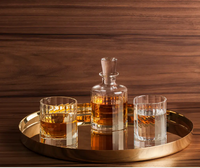 A gold tray displays a glass decanter and two Richard Brendon Fluted Single Old Fashion tumblers, each with amber liquid, set against wood for an Art Deco glassware vibe.