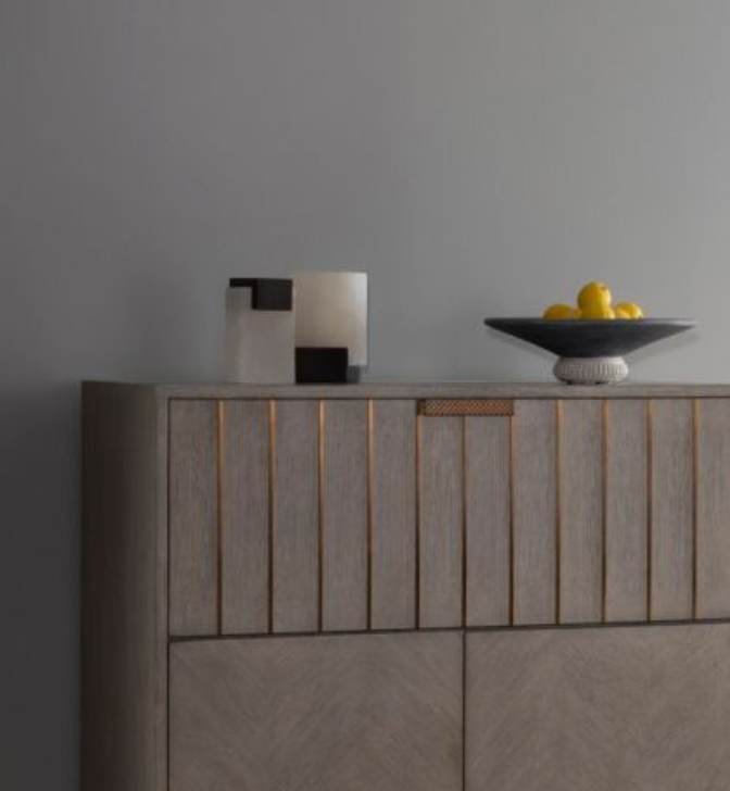 A modern wooden cabinet against a gray wall is topped with decorative sculptures, a dark bowl of yellow lemons, and the Arteriors Tolliver Bookends Set of 2 for added interest.