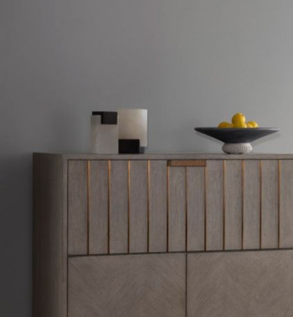 A modern wooden cabinet against a gray wall is topped with decorative sculptures, a dark bowl of yellow lemons, and the Arteriors Tolliver Bookends Set of 2 for added interest.