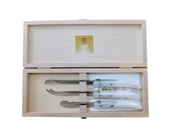 A wooden box with a hinged lid holds the Claude Dozorme Berlingot Cheese 3 Piece Set, featuring three cheese knives with shiny white handles. A gold label and logo are displayed inside the lid, and the set is shown open from above.