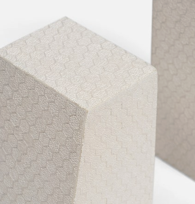 Close-up of two Rene Faux Shagreen Bookends by Made Goods, one in the foreground and one partially seen in the background, both featuring a light tone and subtle hexagonal faux shagreen texture with an architectural edge.