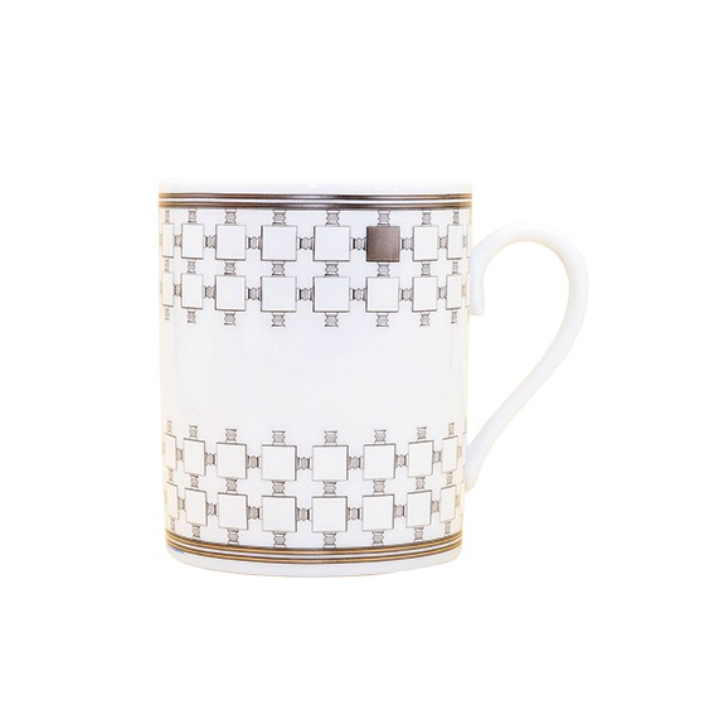 The Home Platinum Dinnerware mug by Robert Haviland & C. Parlon is a white ceramic piece with gold geometric squares, a curved handle, and gold bands at the rim and base—an elegant addition to any luxury tableware collection.