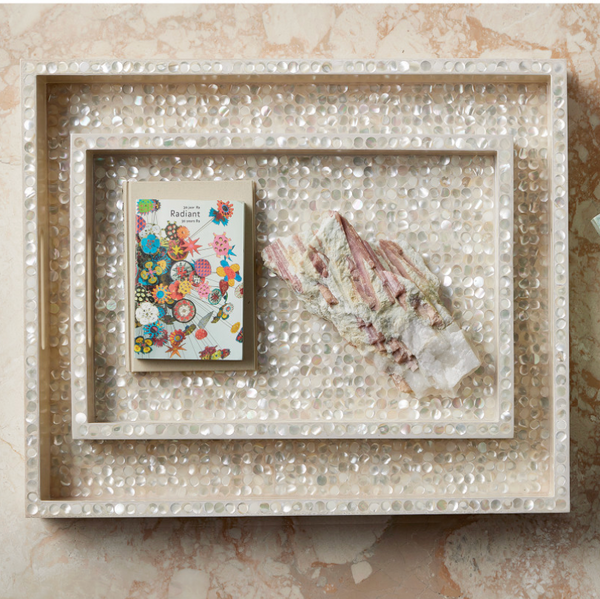 The Graceland Mother Of Pearl Tray by Currey & Company displays a vibrant floral notebook and crystals, adding an elegant luxury decor accent to your marble surface.