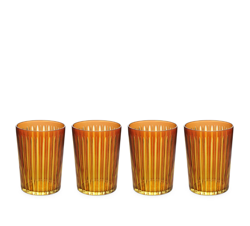 The Prism Highball Set of 4 by L'Objet features amber-colored glasses with vertical ribbed patterns. These stylish, dishwasher-safe tumblers are arranged in a row against a white background, combining elegance and convenience for everyday use.