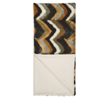 The Chevron Furdi Throw by D.V. KAP / Canaan Company features a chevron pattern in brown, black, white, and blue on one side and solid cream faux fur on the other, partially folded to showcase both luxurious sides.