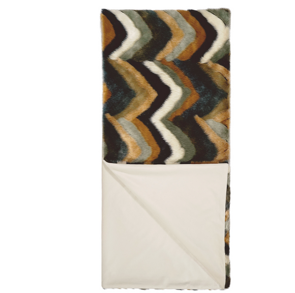The Chevron Furdi Throw by D.V. KAP / Canaan Company features a chevron pattern in brown, black, white, and blue on one side and solid cream faux fur on the other, partially folded to showcase both luxurious sides.