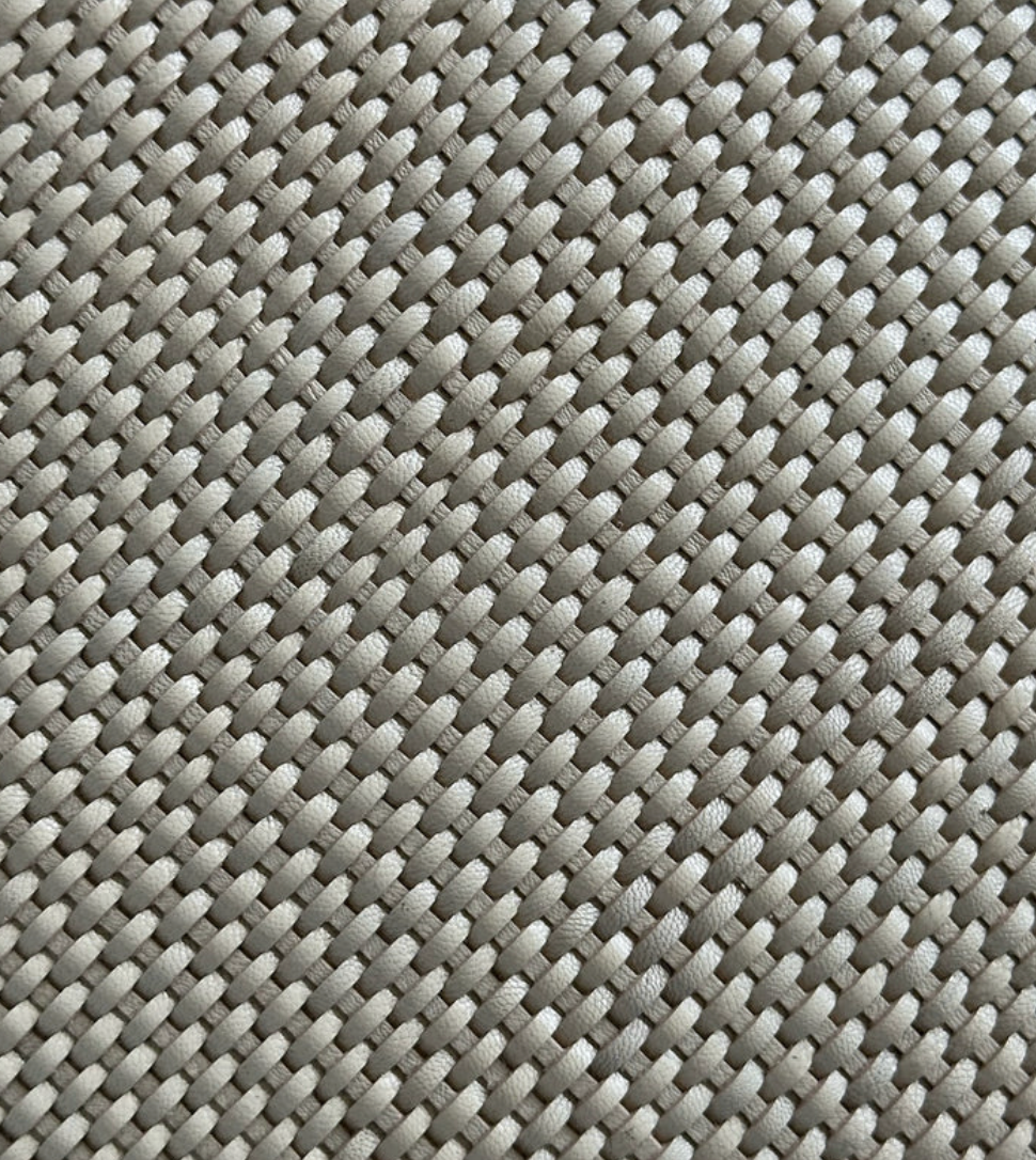 Close-up of the Leather Weave Pillow Ivory by Threads Soft Goods, featuring a beige woven texture with an oval pattern.