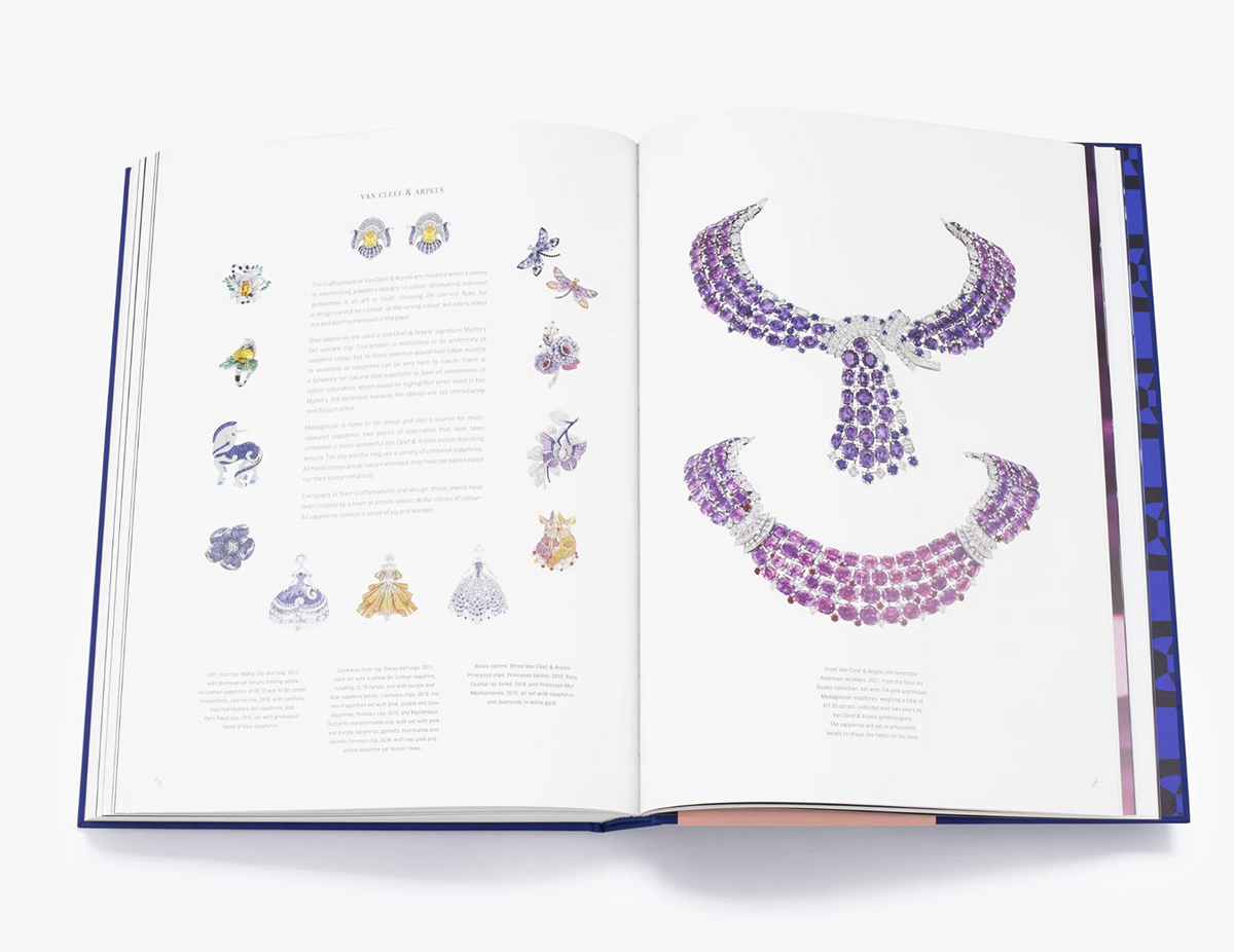 An open book, "Sapphire: A Celebration of Color" by W.W. Norton Company, displays vivid jewelry illustrations—smaller designs on the left page and striking purple gemstone necklaces and collars on the right, evoking a luxurious style.